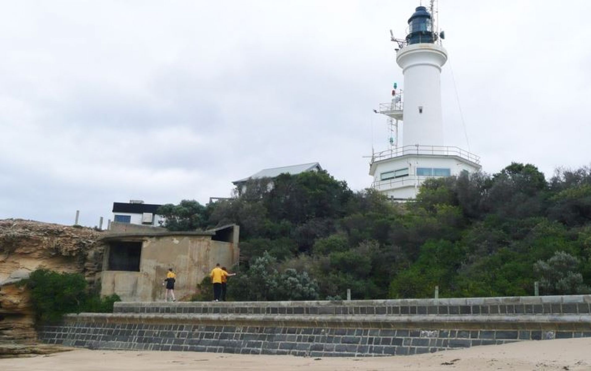 Lighthouse stand tall on the hill overlooking the beach.