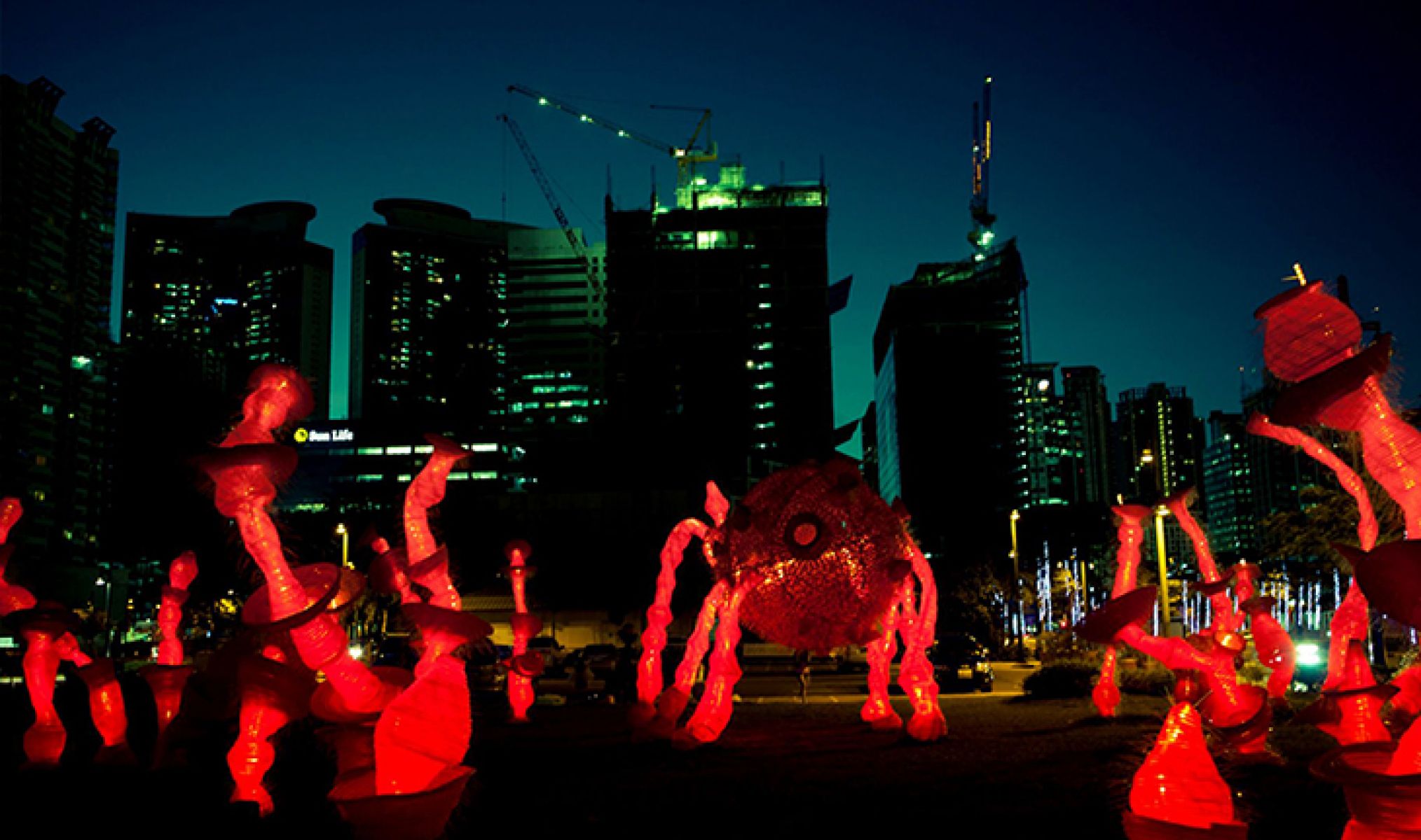Image shows red illuminated creatures in front of Melbourne city buildings at night time